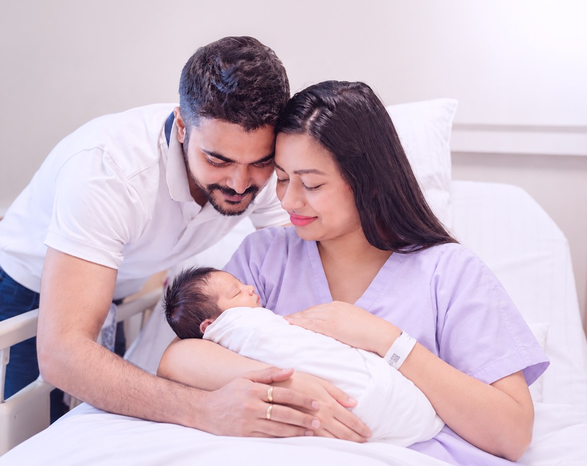 New parents holding their newborn in a hospital room